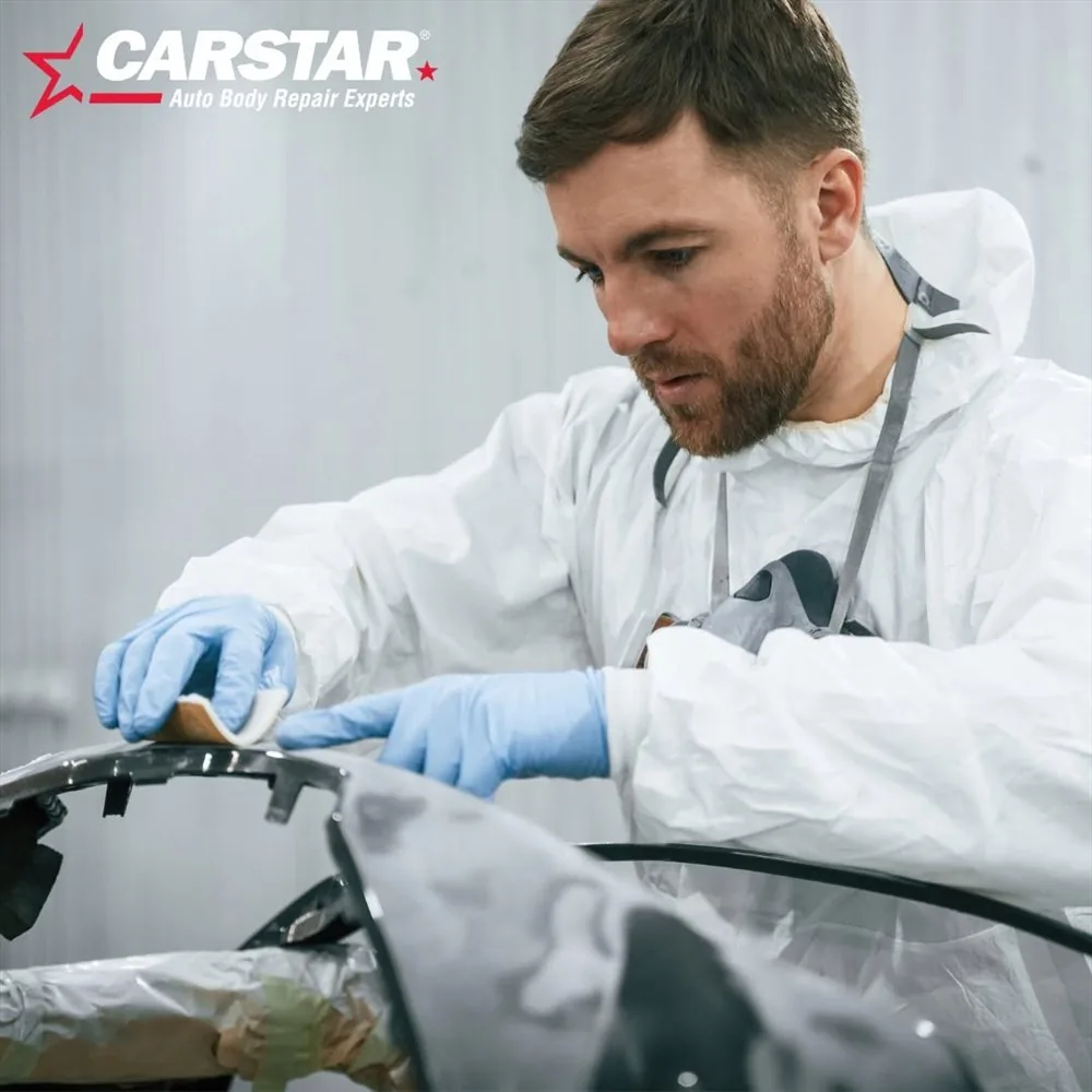 A technician inspecting a vehicle panel during a certified repair